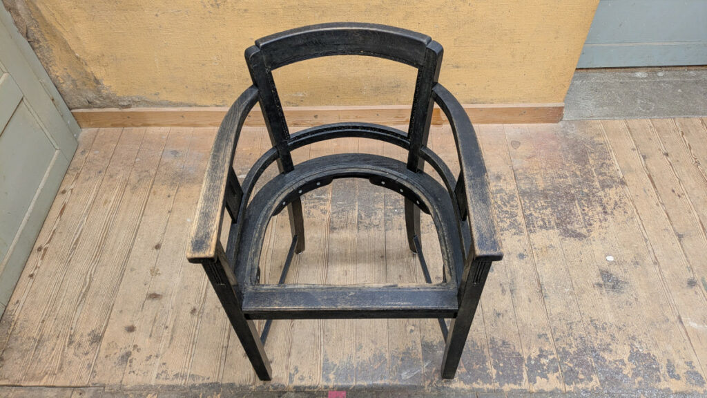 Stuhl restaurieren und stilvoll erhalten Restaurierter Stuhl nach der Reparatur mit stabiler Sitzfläche und schwarzem Gestell.